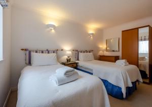 a bedroom with two beds with white sheets and a mirror at Ballard View Apartment in Swanage