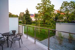 a balcony with tables and chairs and a view of a park at Apartament Loft Mazury in Węgorzewo