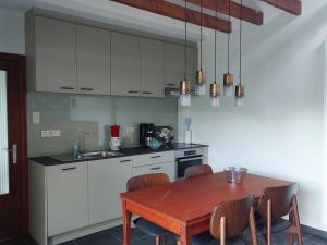 una cocina con mesa de madera y una cocina con armarios blancos. en Vakantiewoning Nieuwdonk, en Berlare