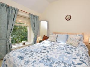 um quarto com uma cama azul e branca e uma janela em 2 Bed in Youlgreave 46087 em Youlgreave
