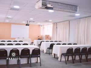 Hoteles Paraiso CHICLAYO في تشيكلايو: قاعة اجتماعات مع طاولات بيضاء وكراسي سوداء