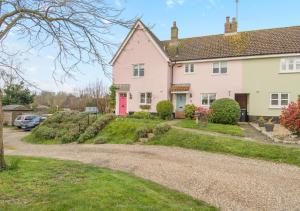 a house with a red door on a gravel road at Honeysuckle in Halesworth