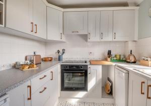 黑爾斯沃思的住宿－Honeysuckle，白色的厨房配有白色橱柜和烤箱