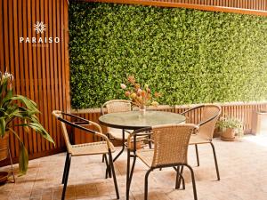 a table and chairs in front of a green wall at Hoteles Paraiso CHICLAYO in Chiclayo