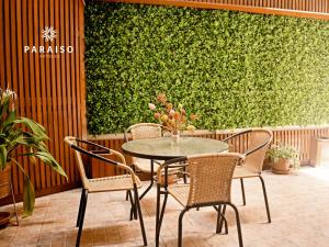 Una mesa y sillas frente a una pared verde. en Hoteles Paraiso CHICLAYO, en Chiclayo