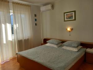 Un dormitorio con una cama con dos almohadas y una ventana. en Sobe Ruža, en Banjol