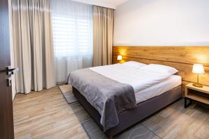 a bedroom with a large bed with a wooden headboard at NOVY Hotel in Zielona Góra