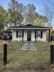 a white house with two chairs in a yard at Love Shack in Foley/ Hot Tub / Modern Cozy in Foley