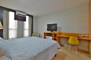 een slaapkamer met een bed, een bureau en een televisie bij Comfort Hotel Taguatinga - Flat Preferido c/ Wifi in Brasilia