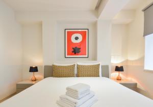 Un dormitorio con una cama blanca con dos lámparas. en Soho 22 Serviced Apartments by Concept Apartments, en Londres
