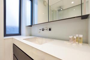 un bagno bianco con lavandino e finestra di Soho 22 Serviced Apartments by Concept Apartments a Londra