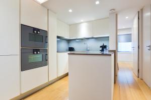 una cucina con armadi bianchi e piano di lavoro di Soho 22 Serviced Apartments by Concept Apartments a Londra