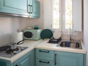 a kitchen with blue cabinets and a sink and a microwave at Artemis by Kallisto Royal Suites in Ornos