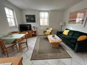 ein Wohnzimmer mit einer grünen Couch und einem Tisch in der Unterkunft Apartmenthaus Aurum in Ahlbeck