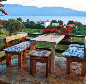 una mesa de madera y bancos con flores en el balcón en Hotel Sirena, en Vlorë