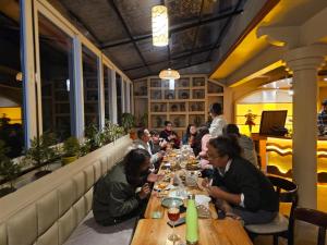 um grupo de pessoas sentadas numa longa mesa num restaurante em Hotel Golden Orchid em Darjeeling