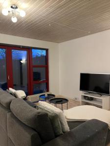 Apartment in Billund في بيلوند: غرفة معيشة مع أريكة وتلفزيون بشاشة مسطحة