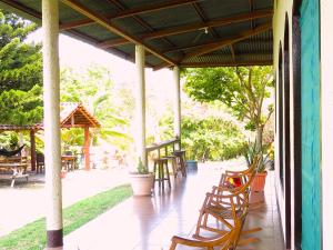 eine Veranda mit Holzstühlen, Tischen und Bäumen in der Unterkunft Casa Reyna in Moyogalpa