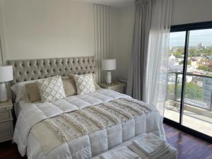 1 dormitorio con 1 cama blanca grande y ventana grande en San Martin Park. Vista 360 a La Plata. en La Plata