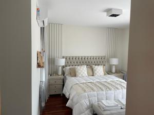 1 dormitorio blanco con 1 cama grande y 2 lámparas en San Martin Park. Vista 360 a La Plata. en La Plata