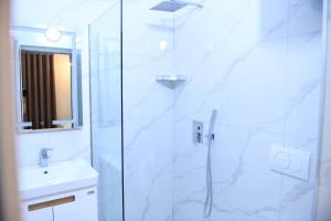 a white bathroom with a shower and a sink at Guest House Cela City Centre in Berat