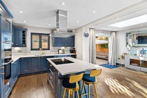 a kitchen with blue cabinets and a island with bar stools at St Chloe in Layer de la Haye