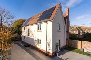 a white house with solar panels on the roof at St Chloe in Layer de la Haye