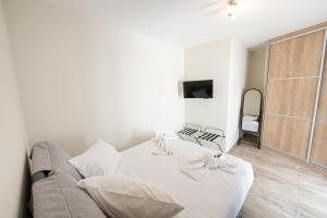 a white bedroom with a couch and a tv at XENIOS APARTMENTS in Poros