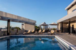 uma piscina com cadeiras e guarda-sóis ao lado de um edifício em Tryp by Wyndham Asuncion em Assunção