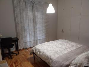 a bedroom with a bed and a desk and a window at Vasiliki's place in Karditsa