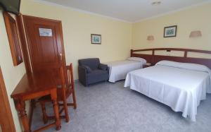 1 dormitorio con 2 camas, silla y piano en Hotel La Costera, en A Lanzada