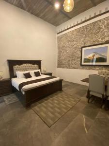 1 dormitorio con cama y pared de piedra en HOTEL BOUTIQUE CASONA 65 en Puebla