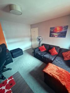 a living room with a black couch and red pillows at Beautiful 3BR Home with Garden & Gym in Hull