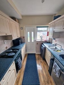 a kitchen with white cabinets and a stove and a sink at Beautiful 3BR Home with Garden & Gym in Hull