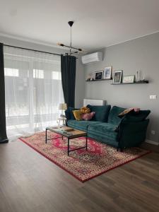 ein Wohnzimmer mit einer grünen Couch und einem Teppich in der Unterkunft Apartment Toucan in Jarocin