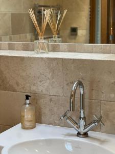 a bathroom sink with a soap bottle sitting on it at The Old Estate Yard, Dumbleton - Near Broadway in Dumbleton