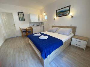 a bedroom with a bed with blue sheets and a kitchen at Guesthouse Apartments Čenić in Budva