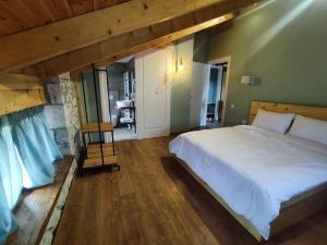 um quarto com uma grande cama branca e pisos em madeira em Vila Nikol em Voskopojë