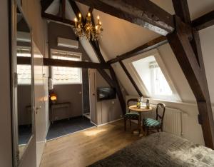 um quarto no sótão com uma mesa e um lustre em B&B De zilveren reiger em Middelburg