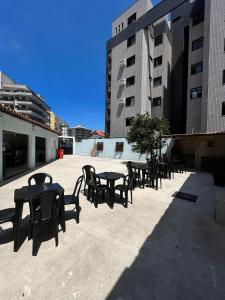 een groep tafels en stoelen op een patio met gebouwen bij Aloha Suites in Cabo Frio