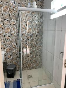 een douche met een glazen deur in de badkamer bij Aloha Suites in Cabo Frio