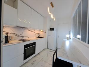 a kitchen with white cabinets and a white refrigerator at Appartement de standing in Créteil