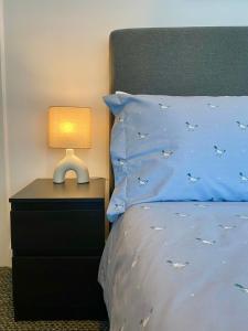a bed with a blue comforter and a lamp on a night stand at Bailey’s Townhouse in Belfast