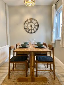 a dining room table with chairs and a clock on the wall at Bailey’s Townhouse in Belfast