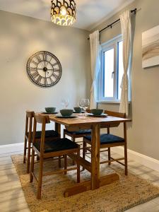 a dining room table with chairs and a clock on the wall at Bailey’s Townhouse in Belfast