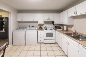 una cocina con electrodomésticos blancos y armarios blancos en The Oasis - A, en Clovis