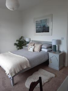 a white bedroom with a large bed and a table at Seasalt Loft in Barmouth