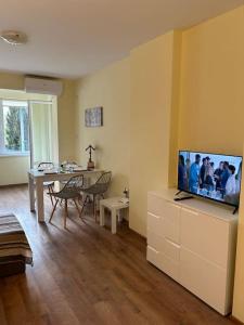 ein Wohnzimmer mit einem TV und einem Esstisch in der Unterkunft Уютен нов апартамент - Стара Загора in Stara Sagora