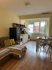ein Wohnzimmer mit einem Sofa und einem Tisch sowie eine Küche in der Unterkunft Уютен нов апартамент - Стара Загора in Stara Sagora