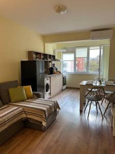 a living room with a couch and a table and a kitchen at Уютен нов апартамент - Стара Загора in Stara Zagora